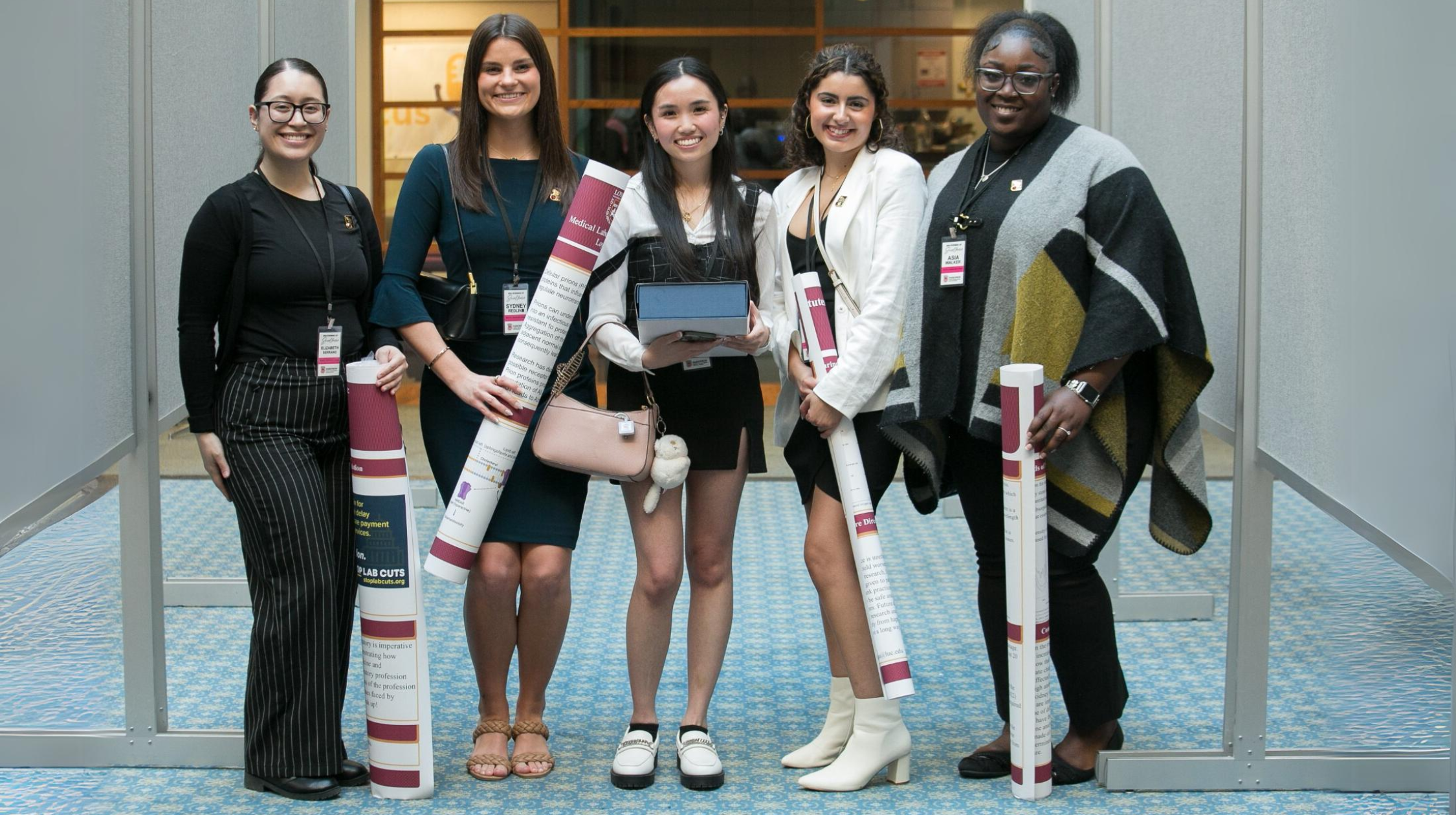 Five students posing for a photo holding their research posters.